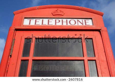 Close up of an old English red telephone box with a blue sky.