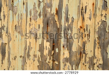 Flaking yellow paint on a wooden garage door.