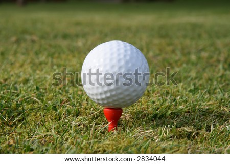 A golf ball on a red tee waiting to be hit.