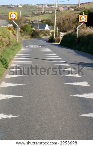 A British road with 30 miles per hour sign and warning markers on the road.
