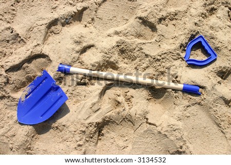 Broken child’s blue spade on a sandy beach.