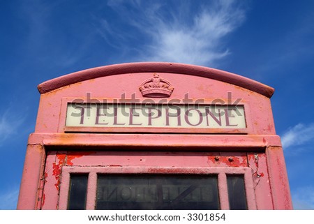 Old faded red British telephone box.
