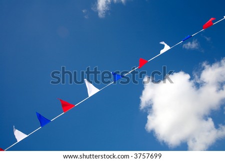 Small red white and blue flags flying in a blue sky.