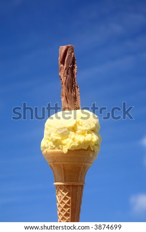 A yellow ice cream with a chocolate flake and a blue summer sky background.