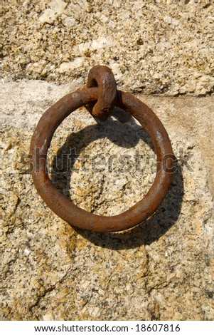 Rusty boat mooring ring on a granite stone wall.