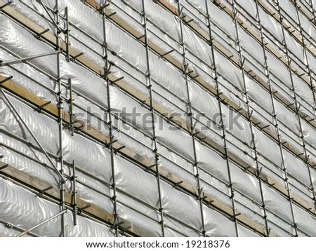 Close up of a high rise building covered in white tarpaulin.