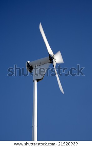 Small electricity generating wind turbine spinning with motion blur movement.
