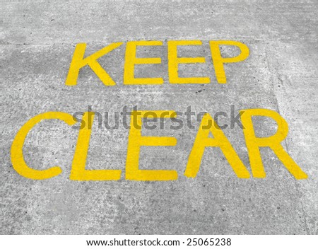 Yellow keep clear sign on a concrete road.