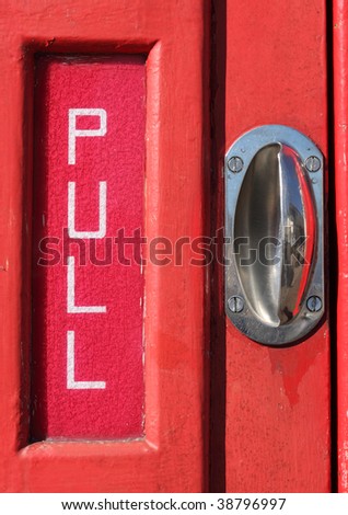 Pull sign and handle on a red telephone kiosk door.