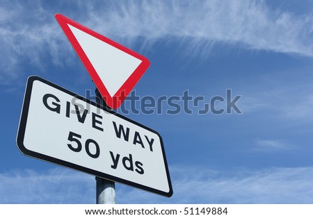 British give way in 50 yards road sign and a blue sky.