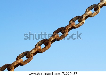 Old rusty metal chain links and a blue sky.