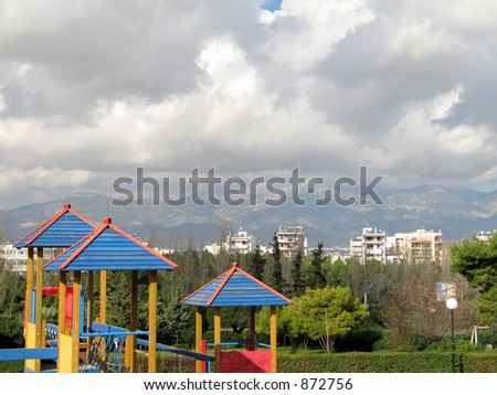 A view of the park, the city (Athens, Greece), the mountain, and the sky, over a wooden construction of a playground