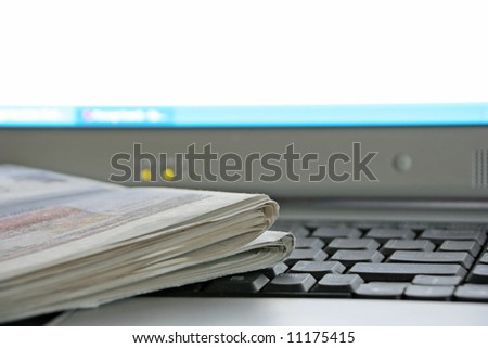 A newspaper on the keyboard of a laptop computer (focus is on the corner of the newspaper)