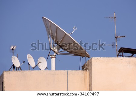 A large tv satellite antenna, together with a few smaller ones and a few TV antennas
