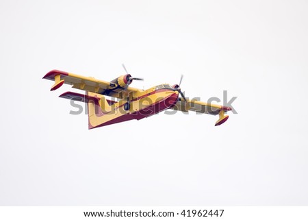 A yellow and red fire fighting airplane flying over