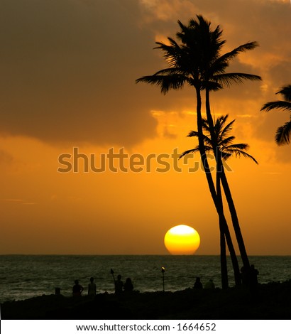 Tropical sunset over the ocean with palm trees and people silhouettes in the foreground