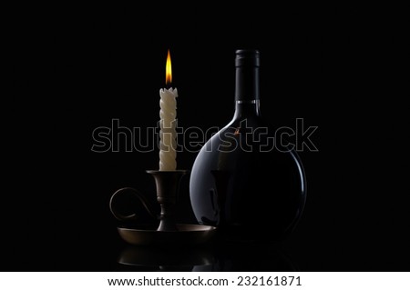 Bottle, candle and glass of wine on black background