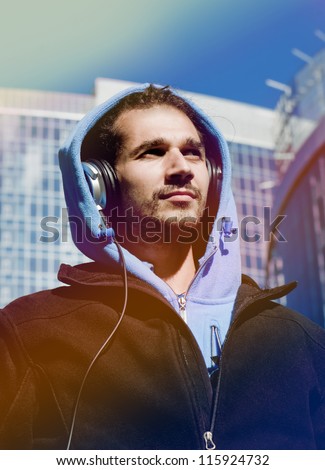 Guy with headphones walking around the city and listening to music