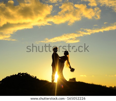 Silhouette of bride and groom, sunset.