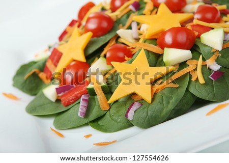 Healthy Spinach Salad with Kid-Friendly Cheese Stars on a White Plate (with focus on front edge of salad)
