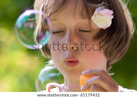 Close up portrait of a little girl\
\
blowing soap bubbles