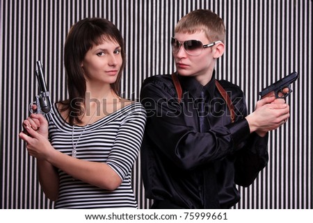 Young couple holding guns over stripe background