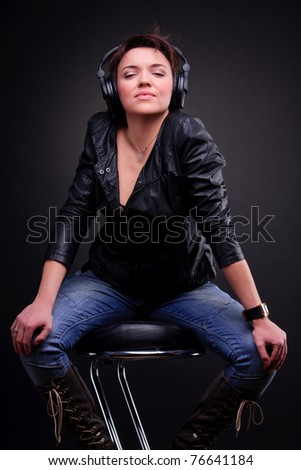 The beautiful girl in headphones sitting on the bar stool