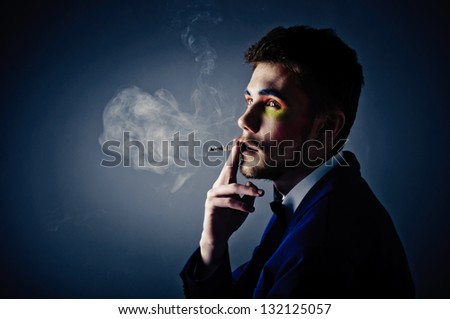 Dark portrait of the young beautiful man. The young man smokes cigarette