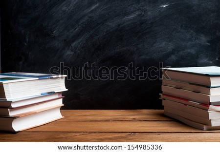 stack of books in front of the black board