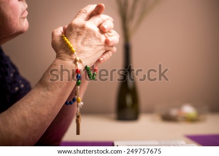 A woman prays to God. In the background holy bible and rosary