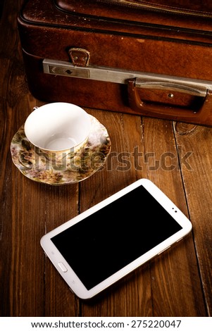 Suitcase and old camera, tablet, phone and a cup of coffee.