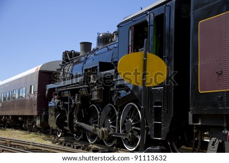 Steam train sitting in the station with carriages