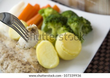 healthy food, a piece of fish on fork with vegetables background