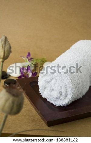 white towel roll on wooden tray for spa treatment