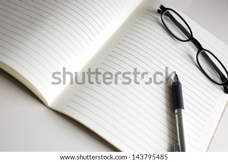 blank notebook pages with pen and glasses