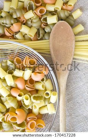 wooden spoon and uncooked pasta on natural fabric