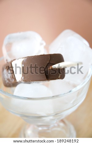 close up stick of chocolate ice cream bar on ice