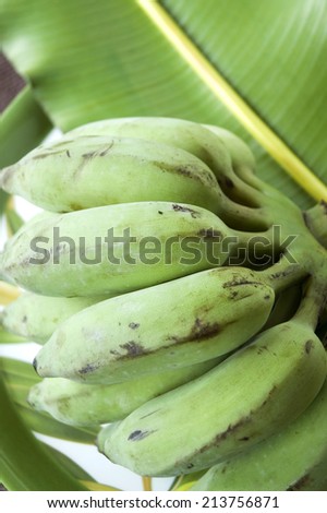 bunch of green banana on banana leaf