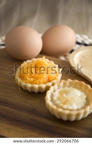 close up sweet mini tart on wooden board with eggs on background