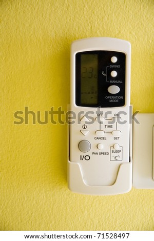 air conditioner remote control on yellow wall.