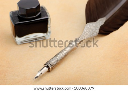 Feather quill and inkwell on an old paper. Photo closeup