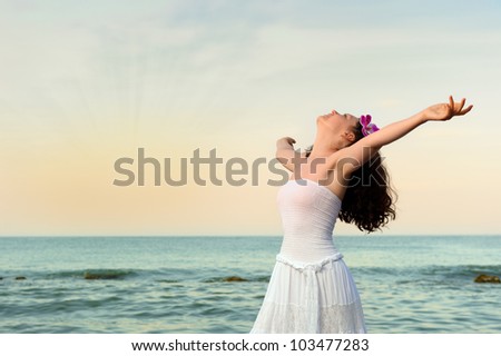 The woman in a white sundress on seacoast. Sunset illumination