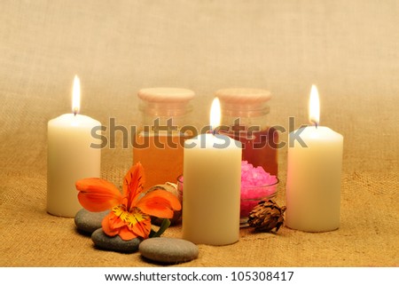 Object for the spa. Candles burning, pebble, a Lily, a bottle with oil, liquid soap, and more.