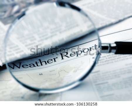Loupe lies on the newspaper with title Weather report.Blue toned. A photo close up. Selective focus
