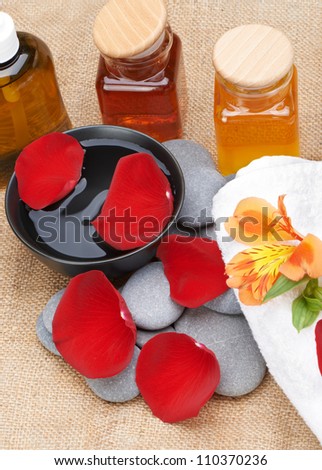 Object for the spa. Pebble, Lily, liquid soap, cupping glass with oil, bowl with the petals.