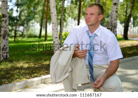 A young businessman in a white shirt with a tie. Photo in the Park