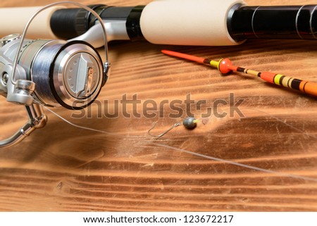 Objects for fishing. The rod with reel, a float, fishing line and hook on a wooden surface
