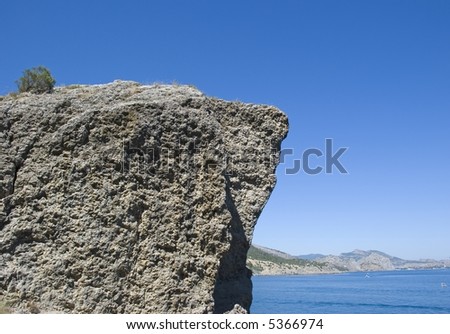 The rock on a background of the blue sky and ocean is high