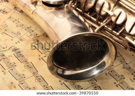 Old saxophone and notes. The Musical instrument laying on notes with classical music of the beginning of 17 centuries