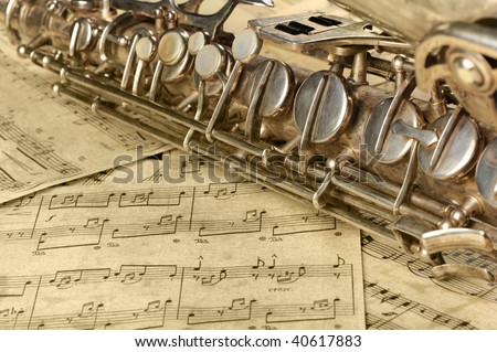 Old saxophone and notes. The Musical instrument laying on notes with classical music of the beginning of 17 centuries